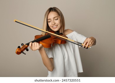 Beautiful woman playing violin on beige background - Powered by Shutterstock