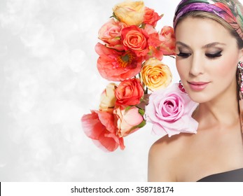 Beautiful woman portrait with glamour makeup and background decorated with artificial colorful flowers. 
