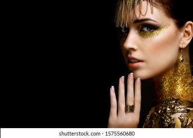 Beautiful woman portrait with golden glitter on her face. Girl with art make-up with golden sparkles. Fashion model with golden makeup