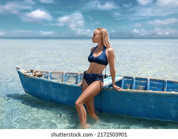 Beautiful woman in a posing near the boat alone in the ocean with clear turquoise water on the beautiful sky background.