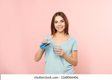 Beautiful woman pouring mouthwash from bottle into glass on color background. Teeth and oral care - Shutterstock ID 1268046406