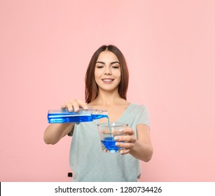 Beautiful woman pouring mouthwash from bottle into glass on color background. Teeth and oral care - Shutterstock ID 1280734426