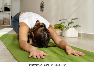 Beautiful woman practices yoga asana Balasana - child`s pose at the yoga studio with plants - Powered by Shutterstock