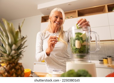 Beautiful woman preparing healthy and delicious green smoothie in a modern kitchen 
 - Powered by Shutterstock