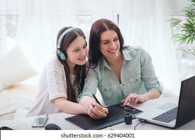 Beautiful woman and pretty teenager girl drawing illustrations together with digital tablet and stylus - Powered by Shutterstock