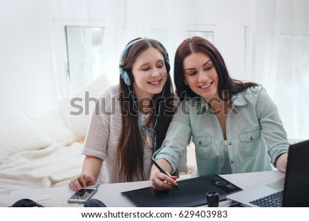 Beautiful woman and pretty teenager girl drawing illustrations together with digital tablet and stylus