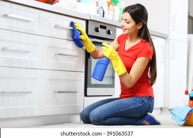 Beautiful Woman In Protective Gloves Cleaning Kitchen Cabinet