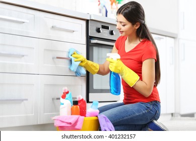 Beautiful Woman In Protective Gloves Cleaning Kitchen Cabinet