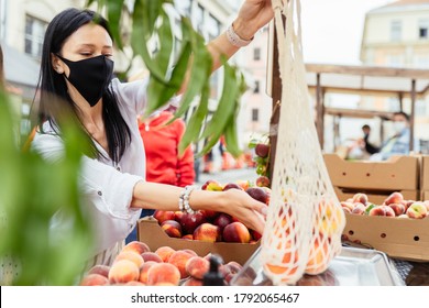 Beautiful Woman In Protective Masks Is Chooses And Weighing Organic Peaches At Food Farmer Market At Summer. Reusable Eco Mesh Bag For Shopping. Zero Waste Concept.