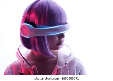 Beautiful Woman With Purple Hair In Futuristic Costume Over White Background. Girl In Glasses Of Virtual Reality. Augmented Reality Game, Future Technology, AI Concept. VR. Blue And Violet Neon Light.