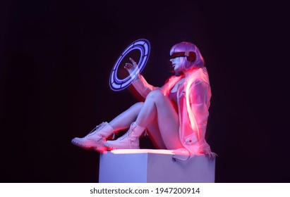 Beautiful woman with purple hair in futuristic costume over dark background. Girl in glasses of virtual reality. Augmented reality game, future technology, AI concept. VR. Neon light.