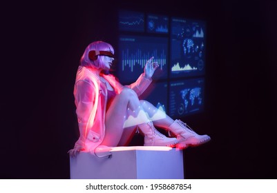 Beautiful woman with purple hair in futuristic costume on dark background. Girl in glasses of virtual reality. Augmented reality game, future technology, AI concept. Holographic interface.