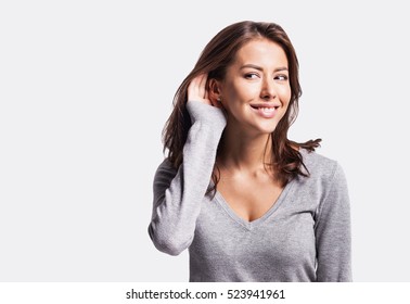 Beautiful Woman Puts A Hand To The Ear To Hear Better. Young Girl Listening Something Over White Background