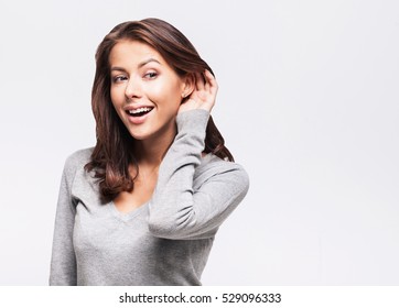 Beautiful Woman Puts A Hand To The Ear To Hear Better. Young Girl Listening Something Over White Background