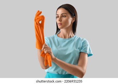 Beautiful Woman Putting Rubber Glove On Light Background