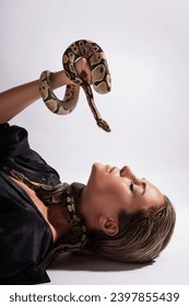 Beautiful woman with python snakes elegantly slithering over her body. 