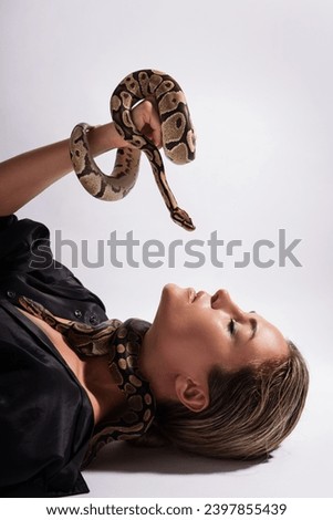 Beautiful woman with python snakes elegantly slithering over her body. 
