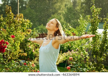 Beautiful woman in the rain in summer garden
