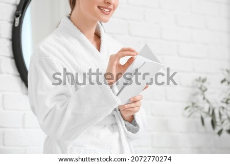 Beautiful woman reading blank magazine in bathroom