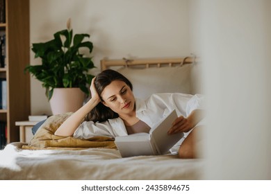 Beautiful woman reading book in bed, cozy, warm and contented feeling. Freedom in story, weekend activity for single woman. - Powered by Shutterstock