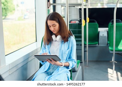 Beautiful woman reads a tablet or ebook in a modern public transport. Young female student rides to the University or college in modern tram. - Powered by Shutterstock