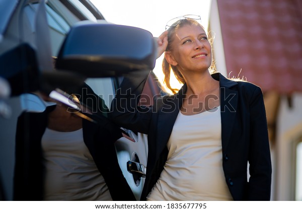 Beautiful woman real estate agent in suit and
black car on the background of the
house