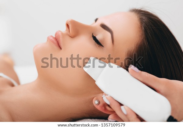 Beautiful woman receiving ultrasonic facial\
exfoliation at spa. Procedure clearing clogged pores, ultrasonic\
treatment for skin\
rejuvenation