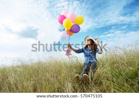 Beautiful woman recreation at meadow with balloons in hand.