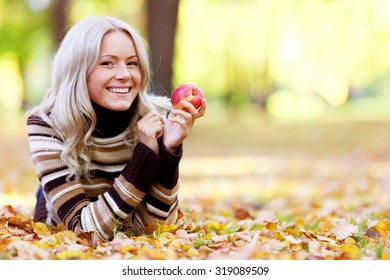 Beautiful Woman With Red Apple In Autumn Park