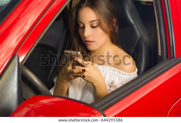 Beautiful woman\
in red car texting in her\
cellphone