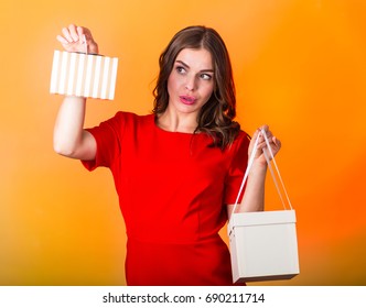 Beautiful woman in red dress holding a present box - Shutterstock ID 690211714