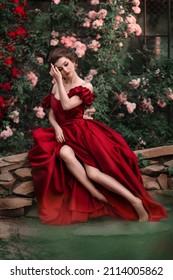 Beautiful Woman In Red Dress Walking In The Garden Full Of Roses.