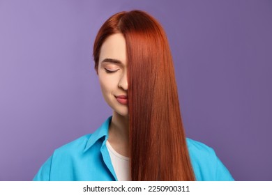 Beautiful woman with red dyed hair on purple background