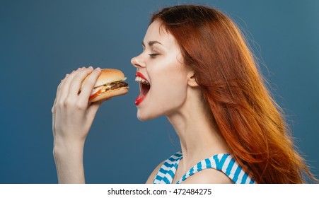 
Beautiful Woman With Red Lips Holding A Burger In Profile And About To Bite