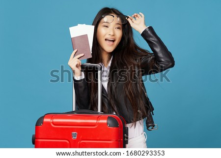Beautiful woman with a red suitcase passport tickets