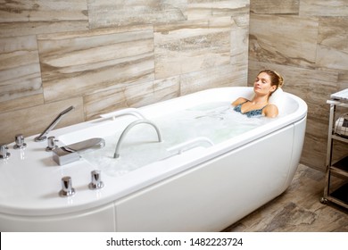 Beautiful woman relaxing in the bathtub having a hydromassage therapy in the SPA