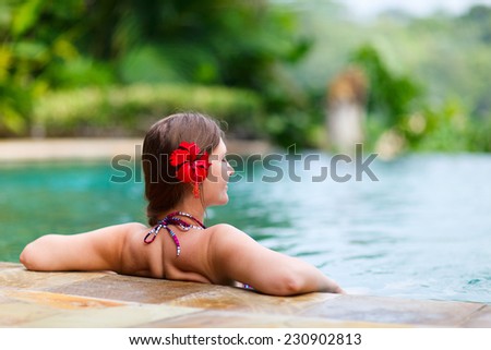 Beautiful woman relaxing in infinity swimming pool