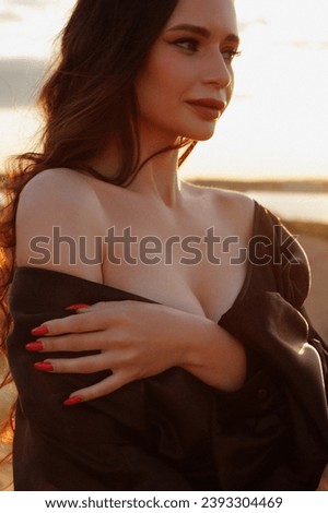 Beautiful woman relaxing on the beach at sunset wearing a black dress and closed eyes. Concept for wellness, travel, relaxation or meditation.