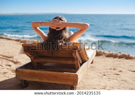 Beautiful Woman relaxing on lounger near a luxurious summer sea beach in hotel Egypt. Concept time to travel