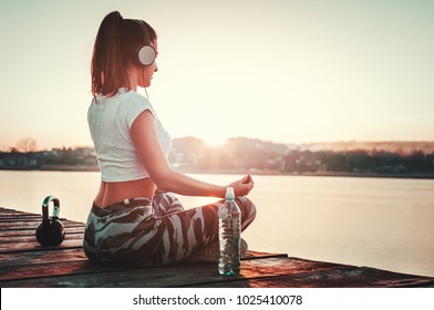 Beautiful woman relaxing outdoors after running workout.Yoga position towards sun - Shutterstock ID 1025410078