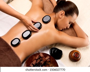 Schöne Frau, die sich im Wellnessbereich mit heißen Steinen auf dem Körper entspannt. Beauty-Therapie