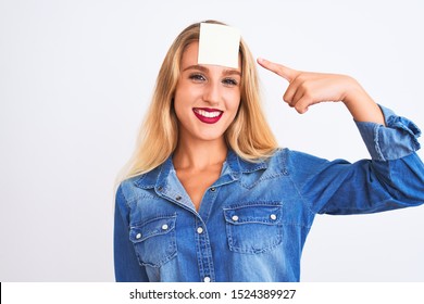 Beautiful woman with reminder sticker paper on forehead over isolated white background very happy pointing with hand and finger