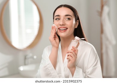 Beautiful woman removing makeup with cotton pad indoors - Powered by Shutterstock