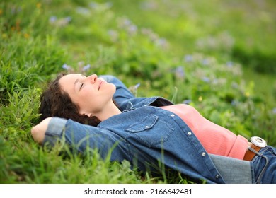 Beautiful woman resting and relaxing lying on the grass in a park - Powered by Shutterstock