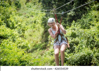 Beautiful Woman Riding A Zip Line In A Lush Tropical Forest