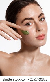 Beautiful woman rub clay mask on her face, doing spa procedure at home, using exfoliating cleansing product, skincare scrub after shower, white background