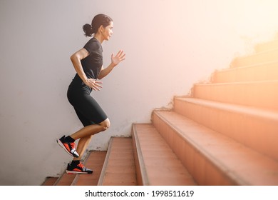 A beautiful woman runner is jogging up the steps under the sunlight. The concept of stepping into success, self-improvement in exercise. - Powered by Shutterstock