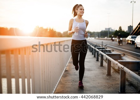 Beautiful woman running over bridge during sunset