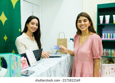 Beautiful Woman And Salesperson Feeling Happy While Paying With Credit Card For Her Shopping At The Beauty Store