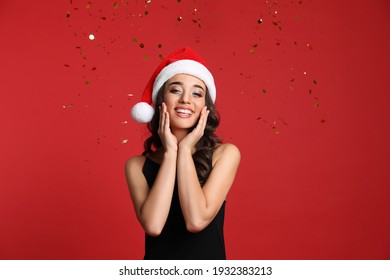 Beautiful Woman In Santa Hat On Red Background. Christmas Party